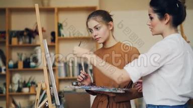 熟练的艺术家经验丰富的老师正在和她的学生交谈，教她<strong>如何画</strong>画，女孩是。